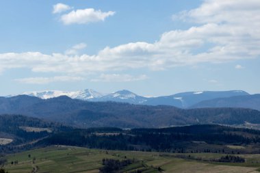 Bulutlu bir yaz gününde Karpat Dağları manzarası. Dağ zirveleri, ormanlar, tarlalar ve çayırlar, güzel doğal manzara..