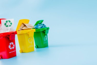 Sarı, yeşil ve kırmızı geri dönüşüm kutularında mavi arka planda geri dönüşüm sembolü var. Şehri düzenli tutar, geri dönüşüm sembolünü bırakır. Doğa koruma kavramı.