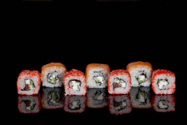 Philadelphia rulosu somon, peynir ve salatalık ile siyah arka planda yansımalı. Suşi Philadelphia.