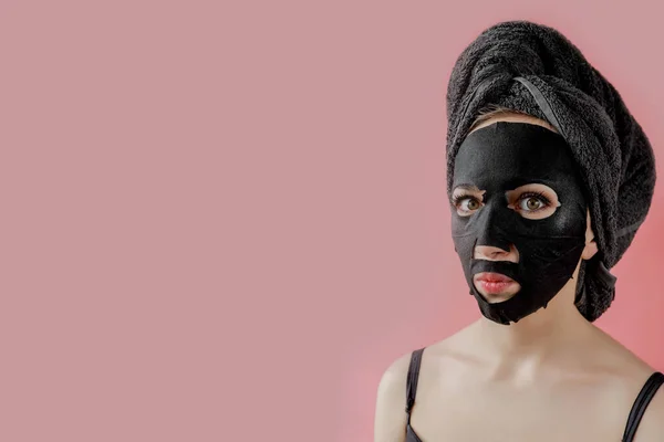 Νεαρή Γυναίκα Εφαρμόσει Μαύρο Καλλυντικό Ύφασμα Μάσκα Προσώπου Ροζ Φόντο — Φωτογραφία Αρχείου