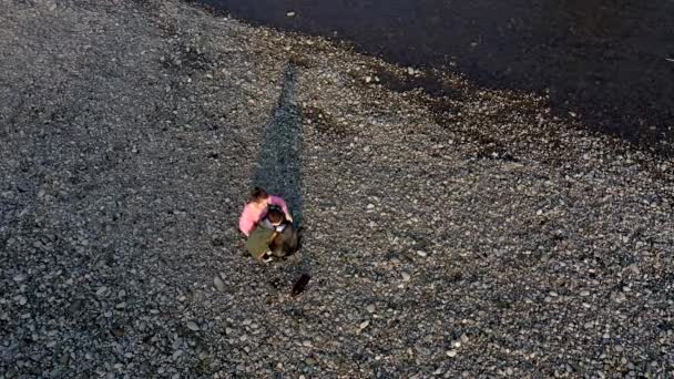 Ung kvinna med sin son samlar plastskräp i en soppåse på floden. Tomma använda smutsiga plastflaskor. Miljöförstöring i land — Stockvideo