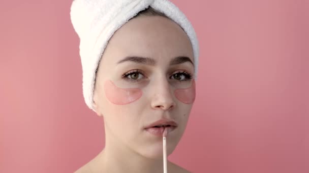 Chica desnuda Plesant aplicando máscaras de colágeno en la cara frente a un espejo. Retrato de la joven feliz sonriendo y posando en el estudio para la publicidad. — Vídeos de Stock