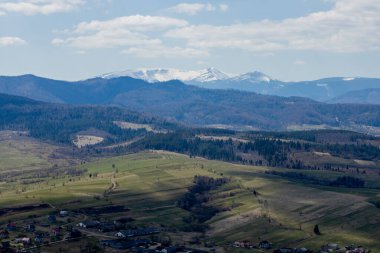 Bulutlu bir yaz gününde Karpat Dağları manzarası. Dağ zirveleri, ormanlar, tarlalar ve çayırlar, güzel doğal manzara..