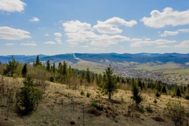 Bulutlu bir yaz gününde Karpat Dağları manzarası. Dağ zirveleri, ormanlar, tarlalar ve çayırlar, güzel doğal manzara..
