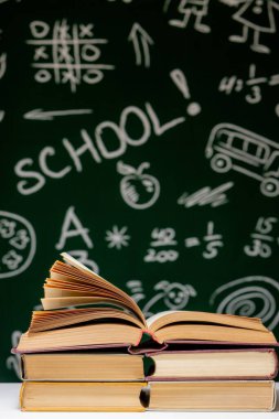 Yeşil karatahta arkaplan üzerine kitap yığını, okul konseptine geri dönüş.