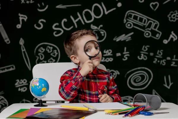 Leuke Slimme Jongen Zit Achter Een Bureau Met Vergrootglas Hand — Stockfoto