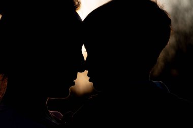 Gün batımında dışarıda oynayan bir anne ve oğlunun silueti. Anneler Günü konsepti.