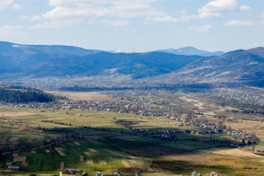 Bulutlu bir yaz gününde Karpat Dağları manzarası. Dağ zirveleri, ormanlar, tarlalar ve çayırlar, güzel doğal manzara..
