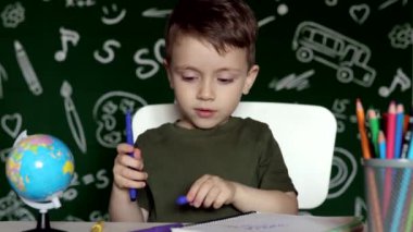 Ev ödevi yapan sevimli çocuk. Masada çizim yapan zeki bir çocuk. Öğrenci çocuk. İlkokul öğrencisi iş yerinde resim çiziyor. Çocuk öğrenmeyi seviyor. Evde eğitim. Okula dönelim. Okuldaki küçük çocuk.