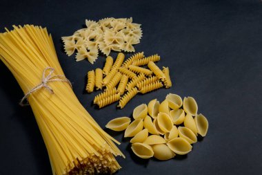 Siyah zemin üzerinde çeşitli makarna türleri. Üst Manzara. Çeşitli makarna çeşitleri. Tasarım için alanı kopyala