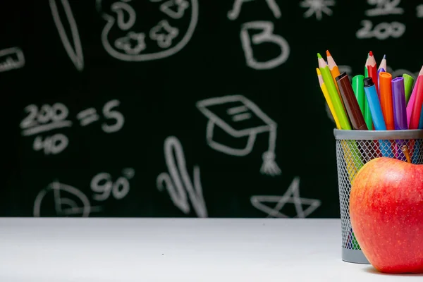 Back to school background with books, pencils and apple on white table