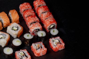 Siyah arkaplanda suşi rulosu. Philadelphia balık, Japon somonu. Lezzetli suşi, pirinç, salatalık, geleneksel wasabi taze, sağlıklı, çiğ gurme..