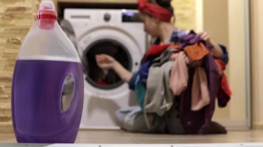 Bir kadın çamaşır yıkar. Bir kadın çamaşır makinesine çamaşır koyar. Ev işleri.