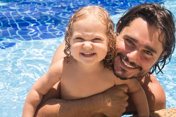 Child girl playing in the pool and hir father — Stock Photo, Image