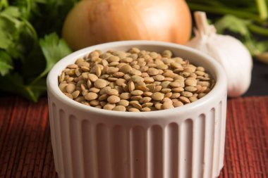 Ahşap bir masa üzerinde bir kapta çiğ mercimek