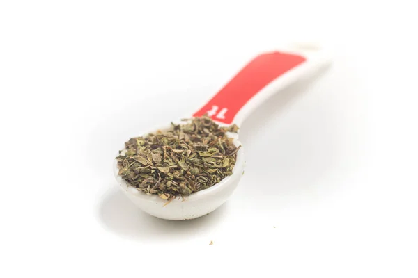 将Oregano炸成白色背景的Teaspoon — 图库照片