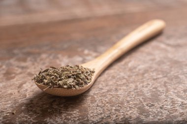 Kurutulmuş Oregano 'yu bir çay kaşığı içinde ahşap bir masanın üzerinde.
