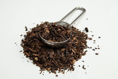 Kızarmış Erva-Mate beyaz arka planda bir ölçüm kaşığı haline getirildi