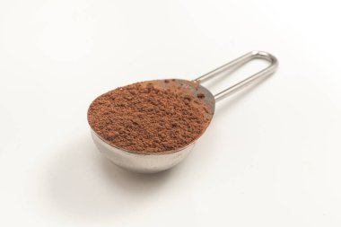 Beyaz arka planda bir kaşık kakao tozu.