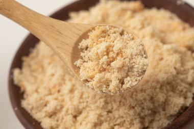 Brezilyalı Farofa. Manioc unu beyaz arka planda tahta bir kaseye konur.