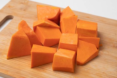 Beyaz arka planda tahta bir tahtada doğranmış balkabağı