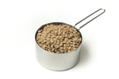 Beyaz arkaplanda izole edilmiş bir kaptaki çiğ mercimek yığını