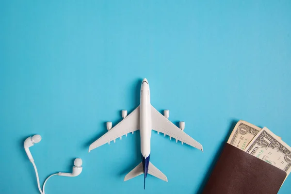 Preparação para viajar conceito, avião, dinheiro, passaporte, fone de ouvido, livro, em fundo azul com espaço de cópia . — Fotografia de Stock