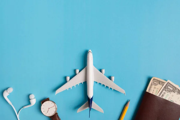Preparação para viajar conceito, relógio, avião, dinheiro, passaporte, lápis, livro, em fundo azul com espaço de cópia . — Fotografia de Stock