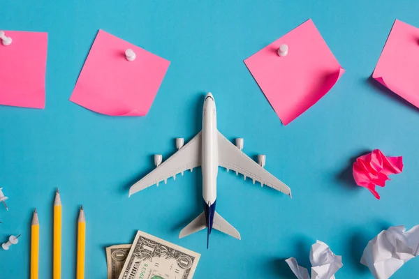 Preparação para viajar conceito, papel anotado, avião, dinheiro, passaporte, lápis, bola de papel, alfinete, no fundo azul com espaço de cópia . — Fotografia de Stock