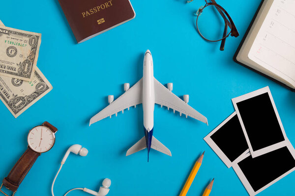 Preparation for Traveling concept, watch, airplane, money, passport, pencils, book, earphone, Photo frame, eyeglass on blue background with copy space.