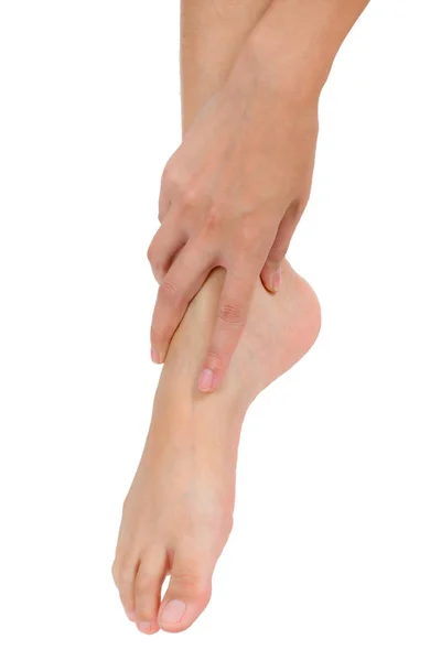 Ženská ruka drží její krásné zdravé nohy a masírovat kotník v oblasti bolesti, izolované na bílém pozadí. — Stock fotografie