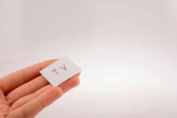 TV w ręku napisany mały biały papier — Zdjęcie stockowe