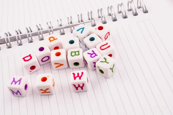 Cubos de letra de alfabeto de várias cores em um caderno em espiral — Fotografia de Stock