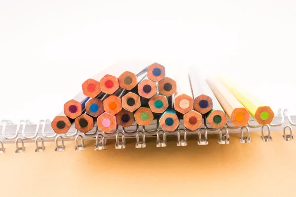 Bir defter yakınındaki çeşitli renk renkli kalemler — Stok fotoğraf