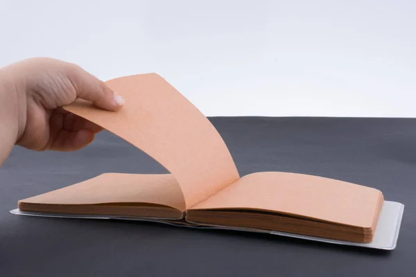 Mano sosteniendo un cuaderno de color marrón — Foto de Stock