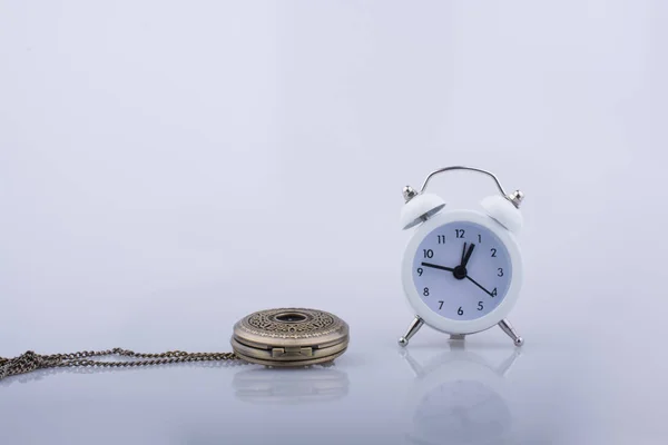 Alarm clock and  a pocket watch side by side — Stock Photo, Image