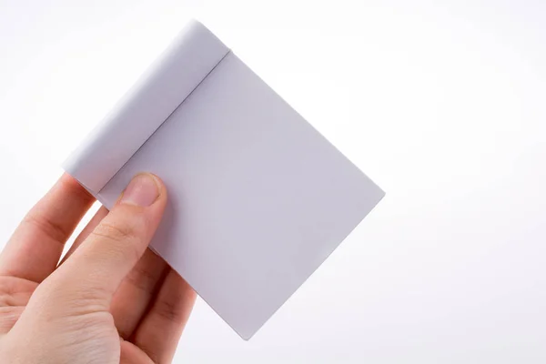 Mão segurando um caderno de cor branca — Fotografia de Stock