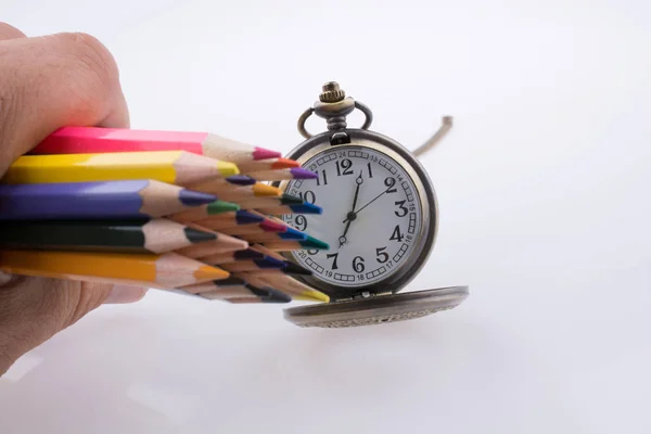 Mão segurando lápis de cor ao lado de um relógio — Fotografia de Stock
