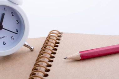 Renkli kalem ve defter üzerinde yerleştirilen bir çalar saat