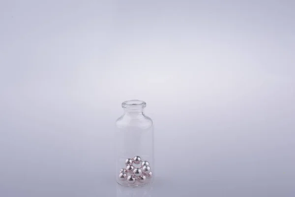 Pequeña botella de vidrio con perlas en la mano — Foto de Stock