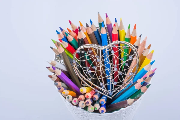 Color Pencils and heart shaped metal wire cage — Stock Photo, Image