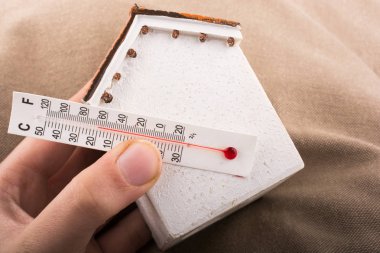 Bir termometre küçük bir modeli ev tutan el