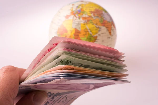 Billets en livres turques tenus à la main à côté d'un globe modèle — Photo