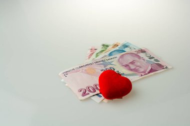 Nesne beyaz zemin üzerine kırmızı renk kalp yan tarafından Türk Lirası banknotların şeklinde