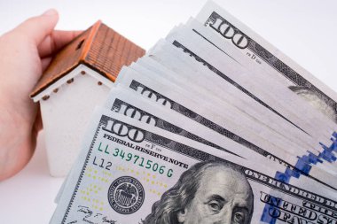 İnsan eli aamerican doları banknot beyaz arka plan üzerinde yan tarafından bir modeli ev tutan