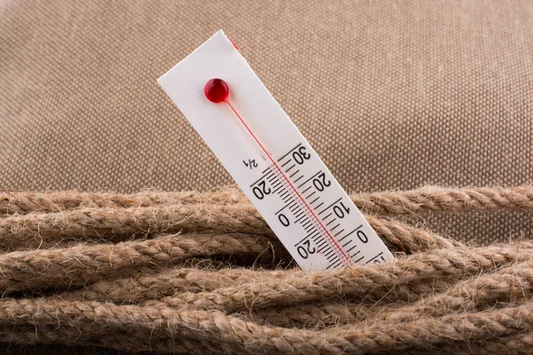 Термометр на коричневій мотузці на тканинному фоні — стокове фото
