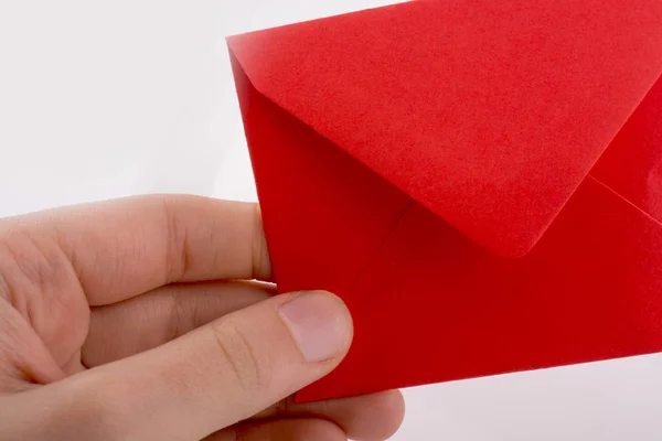 Mão segurando um envelope vermelho no fundo branco — Fotografia de Stock