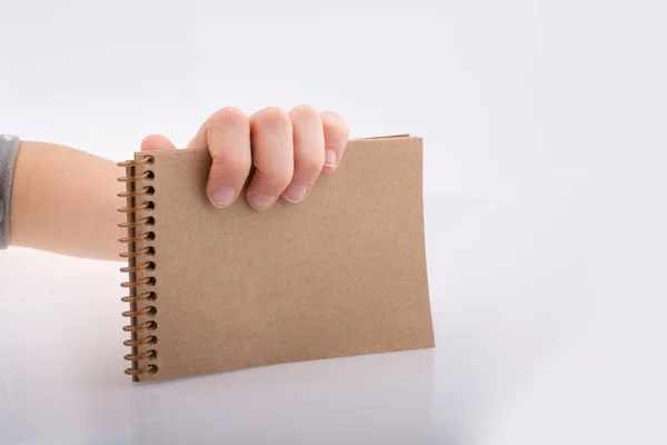 Mano sosteniendo un cuaderno de color marrón —  Fotos de Stock