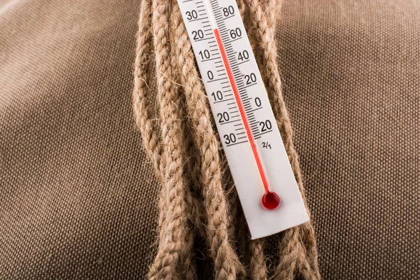 Термометр на коричневій мотузці на тканинному фоні — стокове фото
