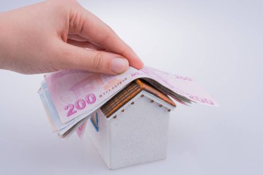 Türk Lirası banknotların bir modeli evin çatısına tutan el